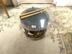A BRASS AND PAINTED DRUM AND STICKS WITH GLASS TO USE AS COFFEE TABLE
