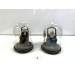 A PAIR OF FIGURES OF ELDERLY LADY AND GENT UNDER GLASS DOMES, 22CMS