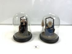 A PAIR OF FIGURES OF ELDERLY LADY AND GENT UNDER GLASS DOMES, 22CMS