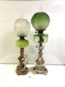 TWO CONTINENTAL PORCELAIN CONVERTED VICTORIAN OIL LAMPS WITH COLOURED GLASS FONTS, GREEN GLASS