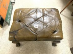 A BUTTONED BROWN LEATHER FOOTSTOOL ON BALL AND CLAW FEET.