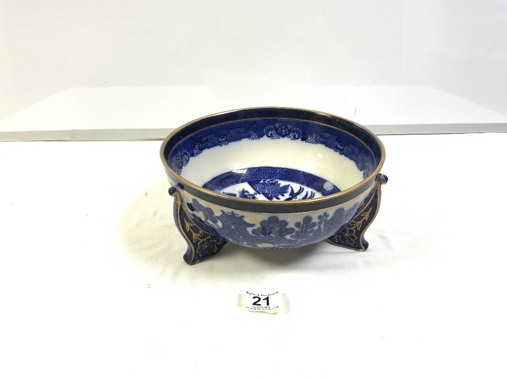 A BLUE AND WHITE GILT DECORATED WILLOW PATTERN BOWL ON THREE FEET (24.5CMS)