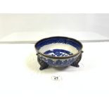 A BLUE AND WHITE GILT DECORATED WILLOW PATTERN BOWL ON THREE FEET (24.5CMS)