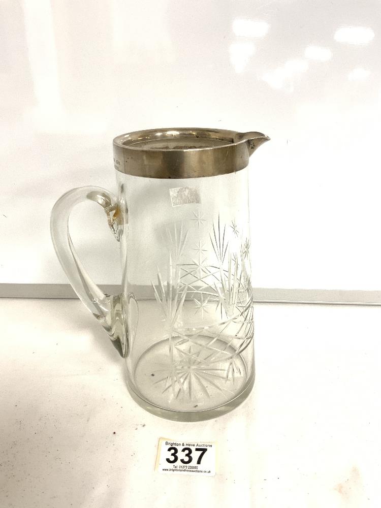 A CUT GLASS WATER JUG WITH A HALLMARKED SILVER RIM. BIRMINGHAM 1919, JOHN GRINSELL AND SONS. 20CMS.