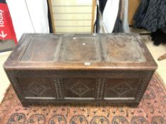 ANTIQUE PANELLED OAK COFFER, WITH LATER CARVING TO FRONT, 126X56X50 CMS.