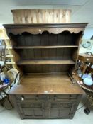 A CARVED OAK DRESSER WITH PLATE RACK, AND TWO DRAWERS AND CUPBOARD BELOW, 18 CENTURY STYLE.