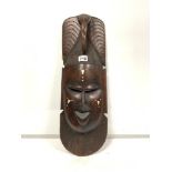 A LARGE HEAVY DARK WOOD HAND CARVED TRIBAL MASK WITH DECORATIVE INLAY, DESIGNED TO REFLECT THE
