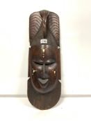 A LARGE HEAVY DARK WOOD HAND CARVED TRIBAL MASK WITH DECORATIVE INLAY, DESIGNED TO REFLECT THE