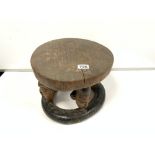 AN UNUSUAL NIGERIAN WOODEN YORUBA STOOL OF CIRCULAR FORM, EACH OF THE FOUR SUPPORTS CARVED INTO