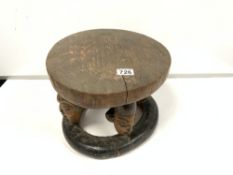 AN UNUSUAL NIGERIAN WOODEN YORUBA STOOL OF CIRCULAR FORM, EACH OF THE FOUR SUPPORTS CARVED INTO