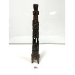 AN HARDWOOD CANDLESTICK HOLDER WITH CARVED DECORATION THROUGHOUT INCLUDING PEOPLE, PALM TREES AND