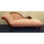 A Victorian upholstered chaise longue of customary form on tapering cylindrical turned supports,