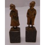 Two continental bronze figurines of a boy and girl in traditional Dutch attire on raised rectangular