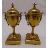 A pair of brass urns, oval with domed pull off covers on raised rectangular bases, 20cm (h)