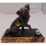An Art Deco bronze figurine of a dog playing with a ball mounted on a rectangular marble plinth,