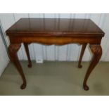 An Edwardian rectangular mahogany games table with gadrooned border on four leaf capped scroll legs,