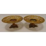 A pair of gilded metal circular scroll pierced stands on leaf chased trefoil bases, 9.5 x 26cm