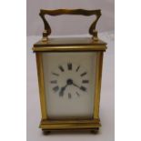 A brass carriage clock of customary form with swing handle on four spool feet, 11cm (h)