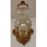 A gilt metal three bottle decanter stand, trefoil on three shell feet, the cut glass decanters