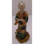 Chinese ceramic figurine of an elder holding a book on naturalistic base, 28.5cm (h)