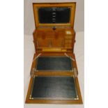 An early 20th century rectangular blonde oak writing cabinet, the hinged cover revealing fitted