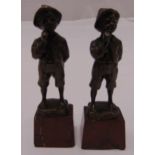 Two bronze figurines of boys in shorts wearing caps on shaped rectangular marble bases