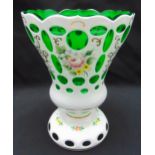 A Bohemian green overlaid conical glass vase decorated with floral sprays on raised circular base,