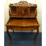 A continental rectangular walnut veneered desk with two drawers and hinged doors surmounted by