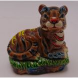 An oriental figurine of a polychromatic porcelain tiger on a raised naturalistic base, marks to