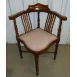 An early 20th century mahogany corner chair with upholstered seat on turned legs with cross