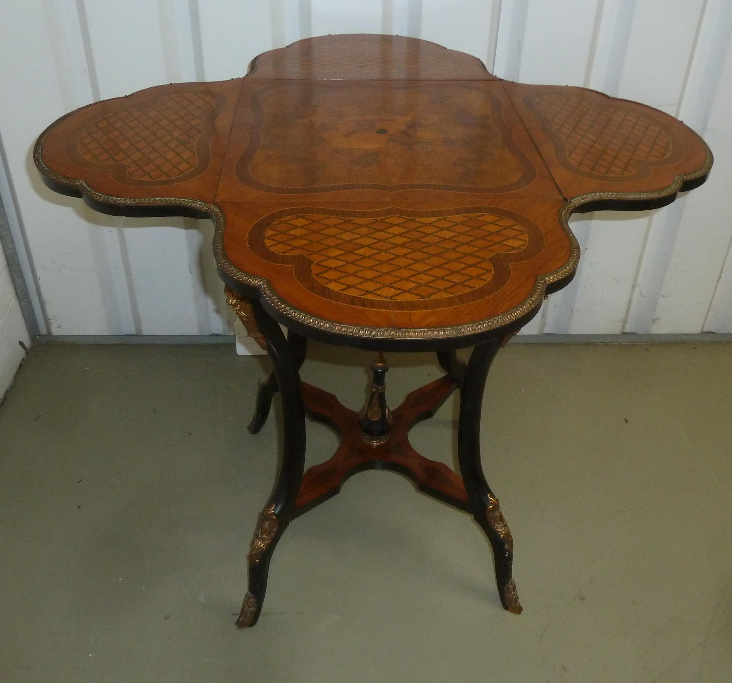 A continental quattrofoil tea table with hinged sides and decorative inlay on four cabriole legs,