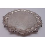 A George IV hallmarked silver circular salver with scroll and shell border and floral engraving to