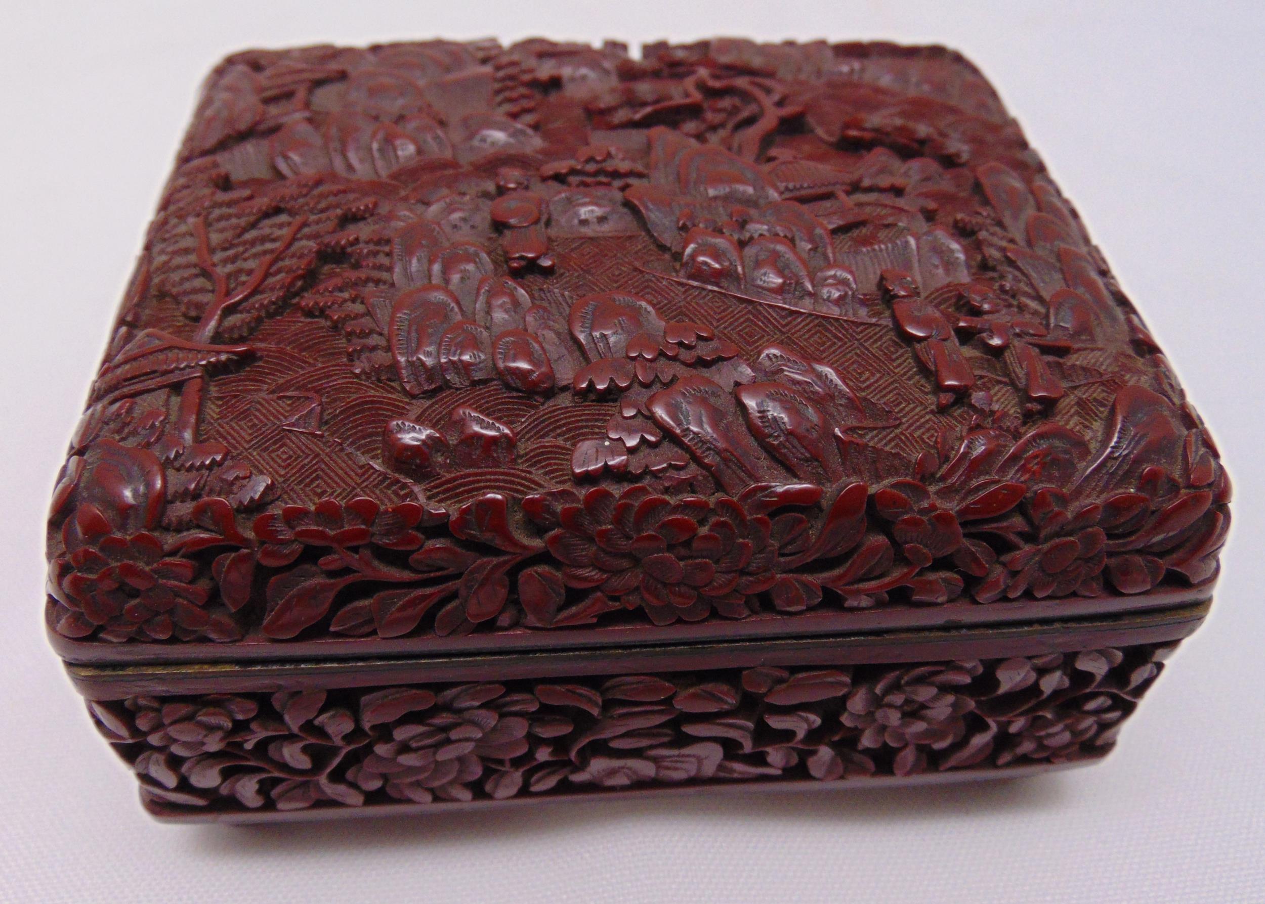 An oriental carved cinnabar lacquer box, rectangular, the hinged cover with figures in a stylised