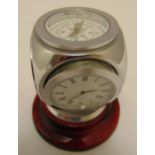 A quartz clock of cubic form with compass, hydrometer and thermometer on raised circular base,