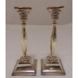 A pair of hallmarked silver table candlesticks, faceted baluster stems on raised square bases with