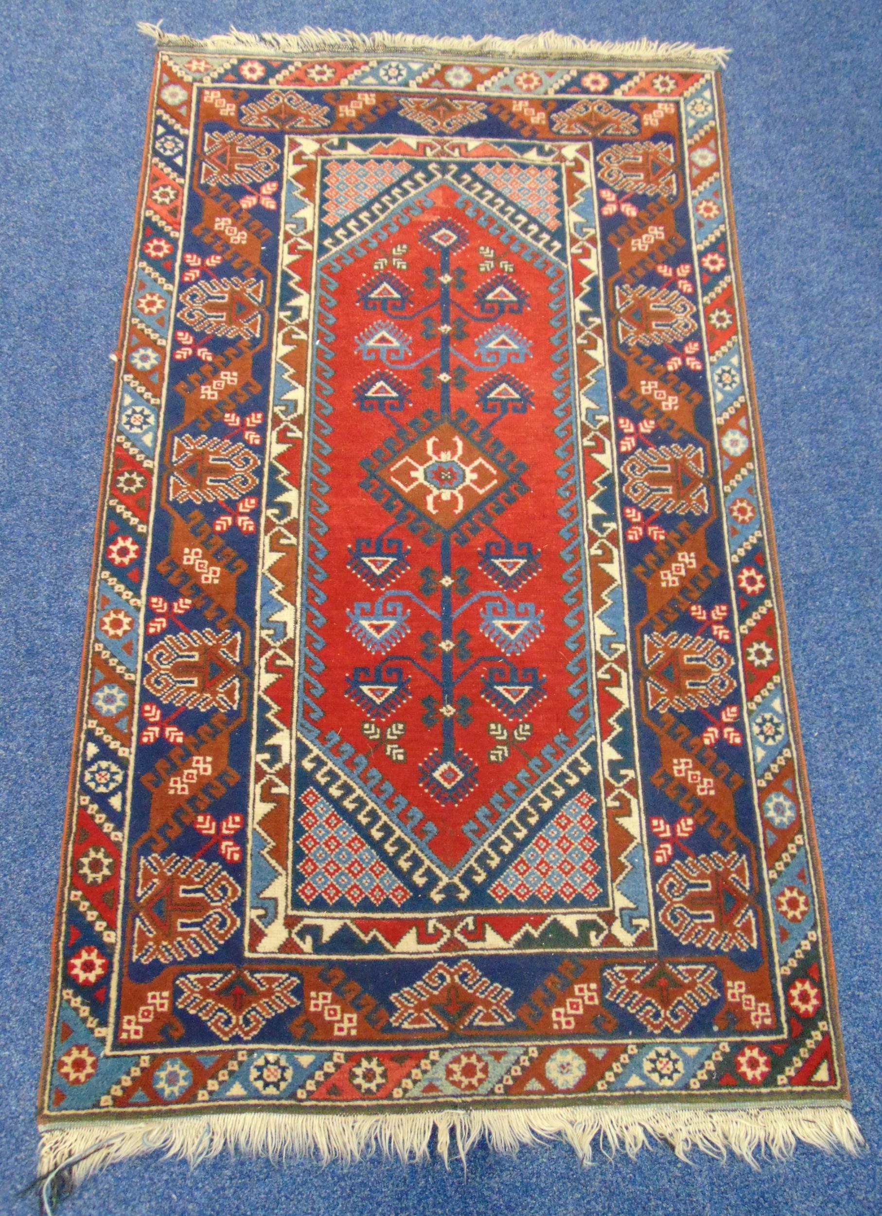A Middle Eastern wool carpet blue and red ground with repeating patterns and border, 207 x 120cm