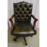 A leatherette button back directors chair with scroll arms on fluted swivel supports and original