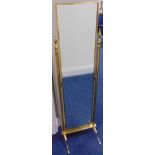 A rectangular brass cheval mirror, the flanking supports with urn finials on four scroll legs, 138 x