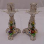 A pair of Dresden porcelain table candlesticks decorated with flowers and leaves on triform bases,