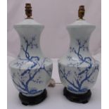 A pair of oriental style blue and white porcelain baluster form table lamps decorated with prunus