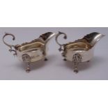 A pair of hallmarked silver sauce boats, oval cut edge leaf capped flying scroll handles on three
