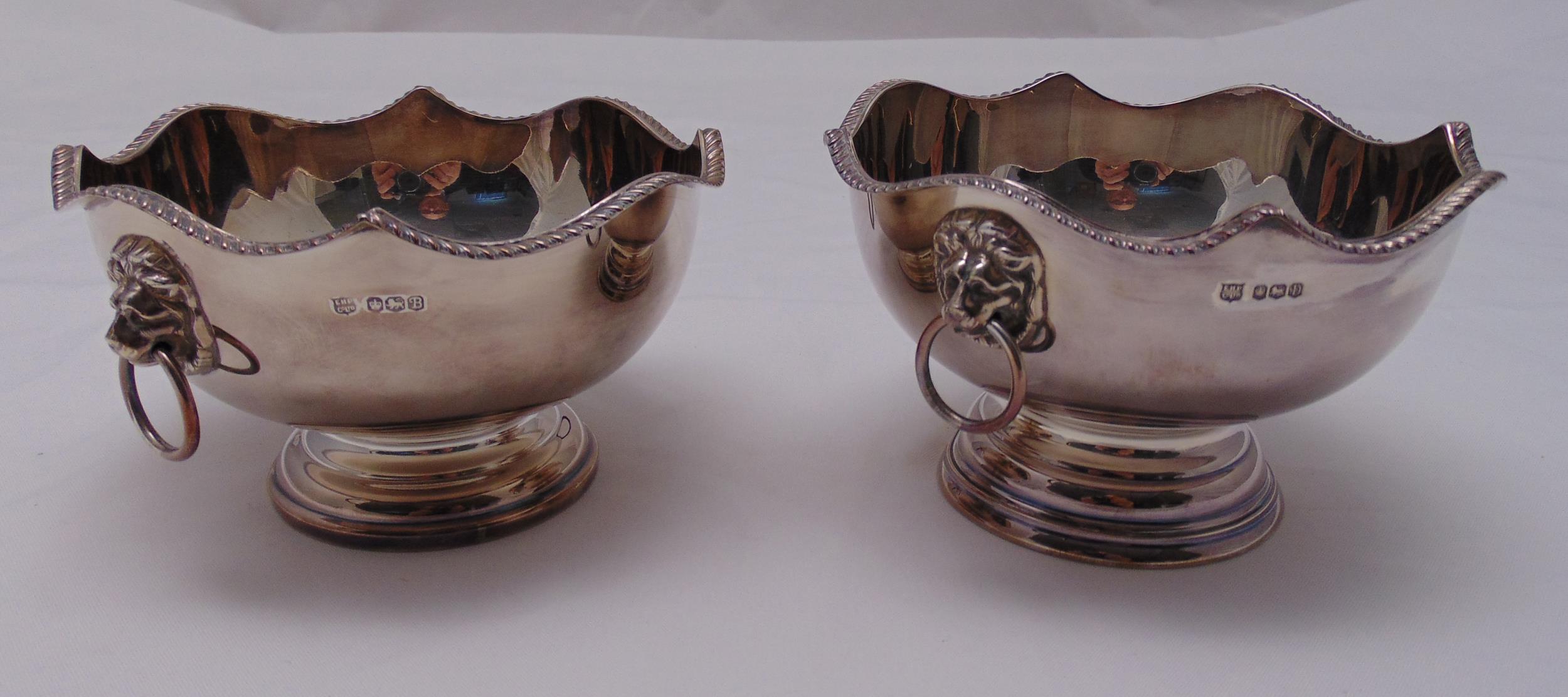 A pair of hallmarked silver bowls with lion mask side handles on raised circular bases, Sheffield