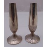 A pair of hallmarked silver table candlesticks tapering cylindrical with bark finish to raised