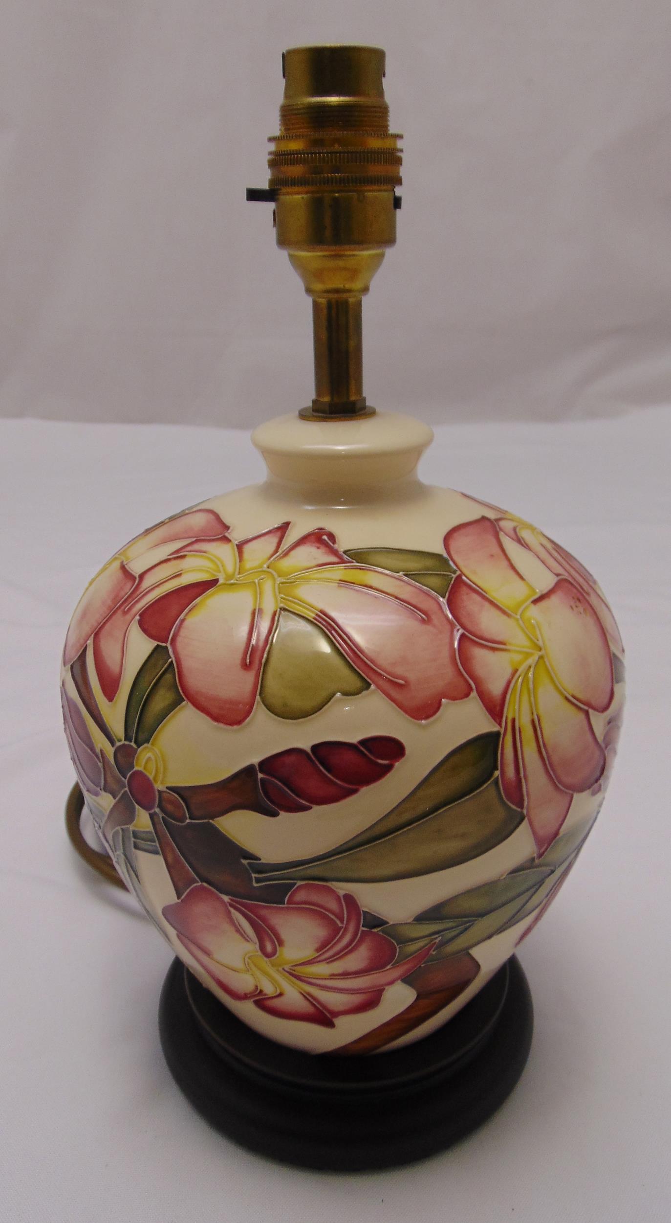 A Moorcroft baluster form table lamp decorated with flowers and leaves on circular wooden base, 29cm