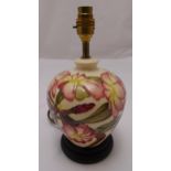 A Moorcroft baluster form table lamp decorated with flowers and leaves on circular wooden base, 29cm