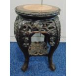 An oriental hardwood garden seat carved with leaves and flowers and marble inset to the top on