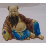 An oriental ceramic figurine of Lohan in relaxed pose, 11cm (h)