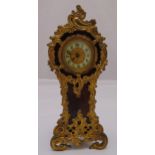 An early 20th century desk clock shaped oval form with applied gilded metal mounts white enamel