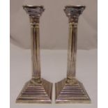 A pair of hallmarked silver Corinthian column table candlesticks on stepped square bases London