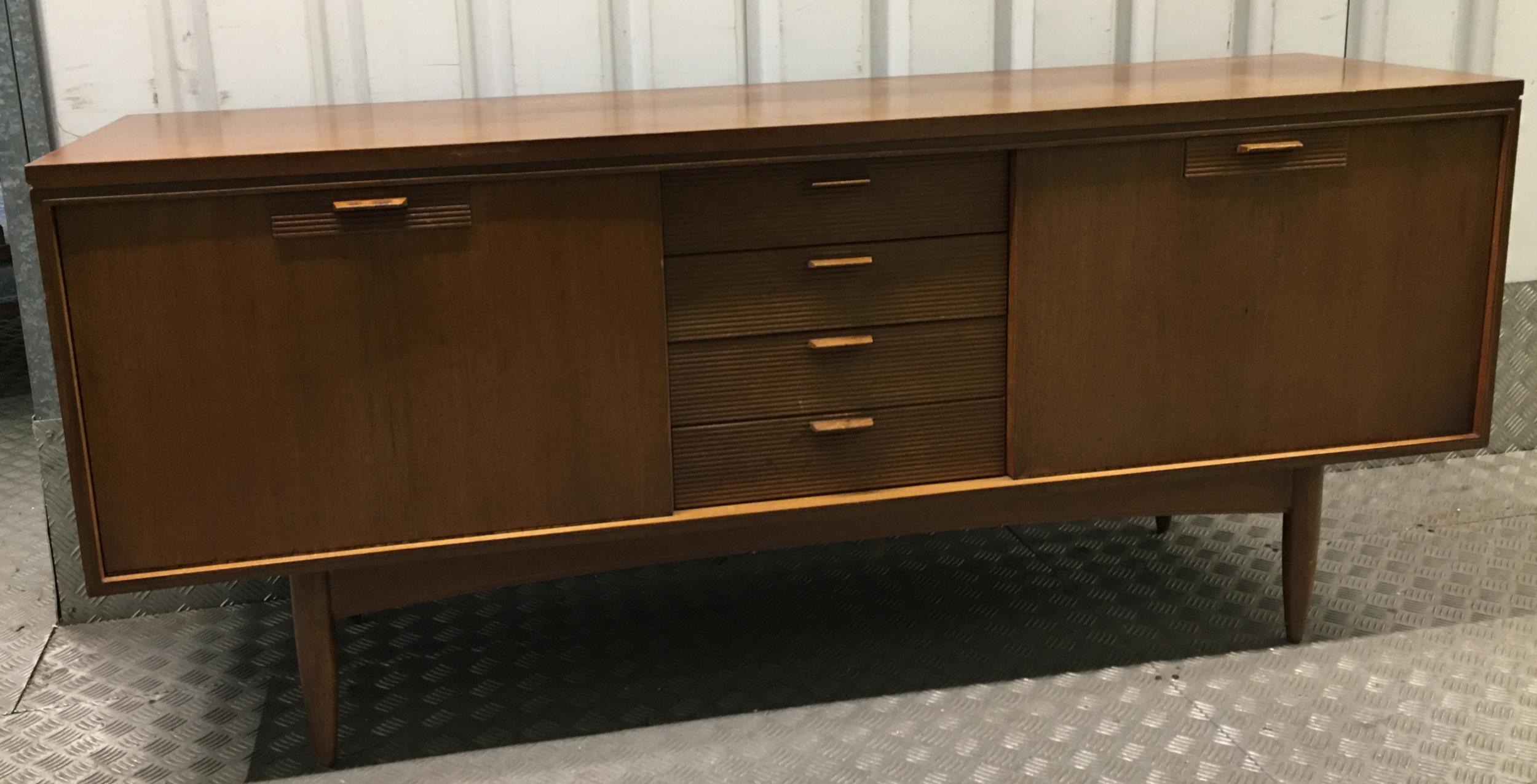 A mid 20th century rectangular teak sideboard with hinged cupboards and drawers on four tapering